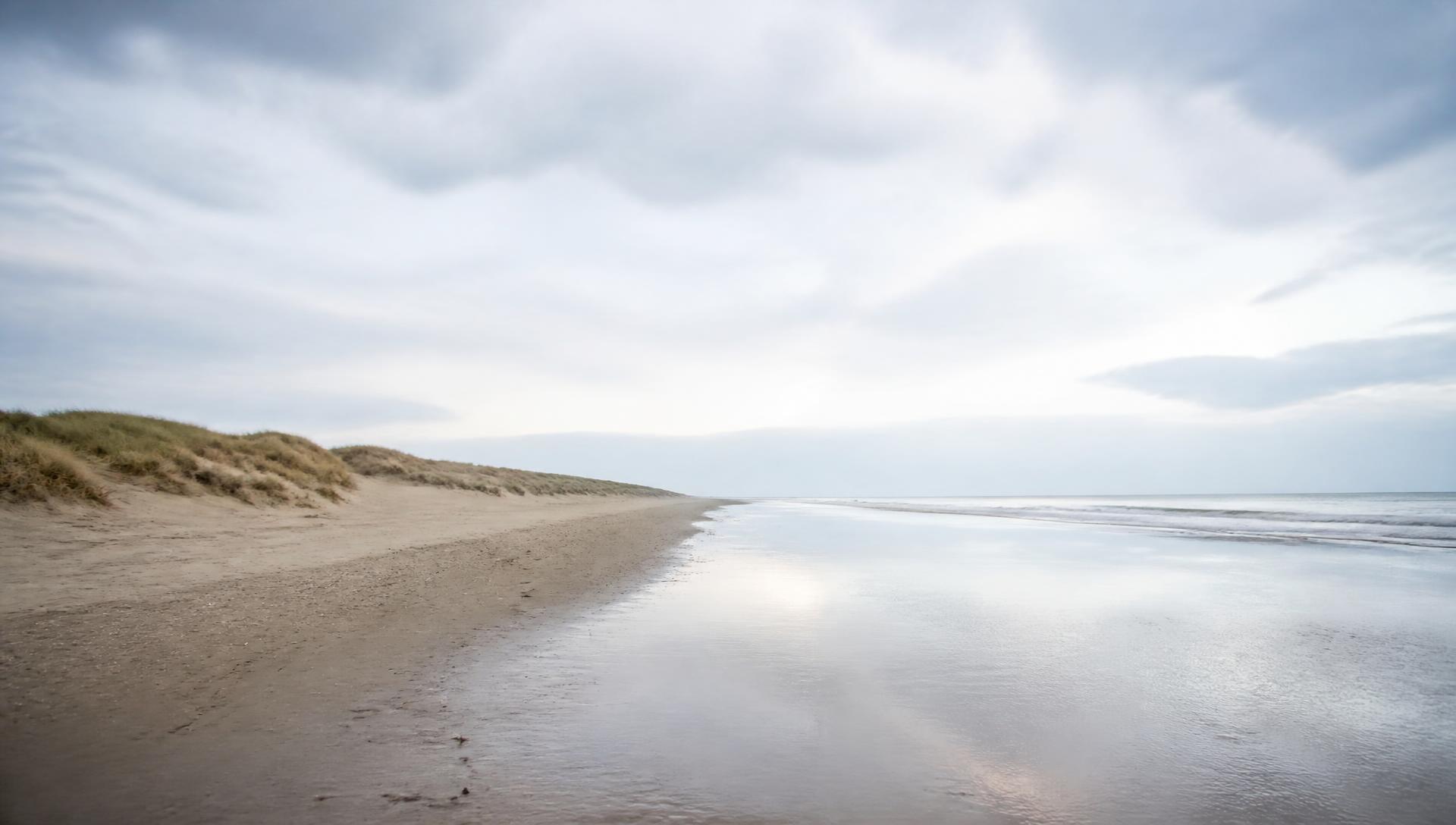 Leeg strand met duinenrij onder een wijde lucht op Vlieland