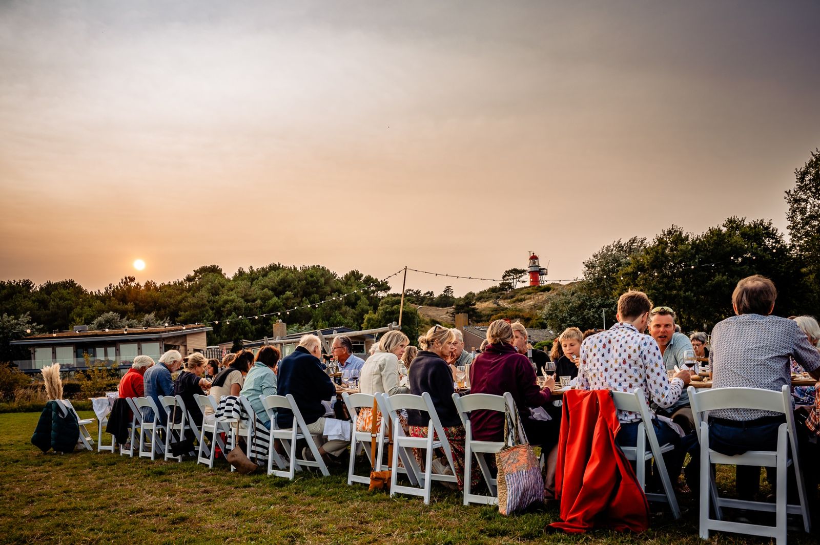 Diner aan lange tafels bij zonsondergang